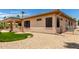 Back exterior view showcasing a well-maintained yard with stone accents and covered patio at 20332 N Denizen Dr, Surprise, AZ 85387