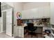 Home office featuring wall-to-wall desk space and white cabinets, with an open doorway on the left at 20332 N Denizen Dr, Surprise, AZ 85387