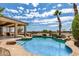Lush backyard with a stunning pool, a covered patio, and views of mature trees and the surrounding mountains at 20332 N Denizen Dr, Surprise, AZ 85387