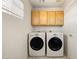 Bright laundry room with front loading washer and dryer, wood cabinets, and tile flooring at 3025 E Fremont Rd, Phoenix, AZ 85042