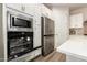 Modern kitchen showcasing stainless steel appliances, white cabinets, and an open oven door at 32611 N 20Th Dr, Phoenix, AZ 85085