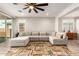 Spacious living room featuring a large sectional sofa, ceiling fan and wood-look tile floors with natural light at 32611 N 20Th Dr, Phoenix, AZ 85085