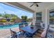 Relaxing covered patio with dining set, ceiling fan, and view of the sparkling pool with rock waterfall feature at 35701 N Bandolier Dr, San Tan Valley, AZ 85144