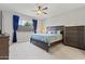 Spacious bedroom features a ceiling fan, dark wood furniture, neutral carpet and blue curtains allowing ample natural light at 10165 E Gamma Ave, Mesa, AZ 85212