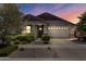 Beautiful home at dusk featuring desert landscaping, warm lighting, and a two-car garage at 10165 E Gamma Ave, Mesa, AZ 85212