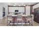 A well-lit kitchen boasts granite counters, white cabinets and pendant lighting over the island with barstool seating at 10165 E Gamma Ave, Mesa, AZ 85212