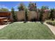 Private backyard oasis featuring an artificial lawn, a patio, and mature trees and flowering shrubs at 12421 N 41St Pl, Phoenix, AZ 85032