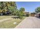 Well-kept home featuring a spacious lawn, brick pathway, mature trees, and a brick driveway leading to a wooden gate at 1274 E Edgemont Ave, Phoenix, AZ 85006