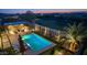 Aerial view of the pool, seating areas, and outdoor kitchen in a beautifully landscaped backyard at dusk at 17018 W Saguaro Park Ln, Surprise, AZ 85387