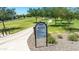 Welcome to Asante Park sign showcases community guidelines, featuring a paved path and lush landscaping for serene recreation at 17018 W Saguaro Park Ln, Surprise, AZ 85387