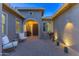 Inviting front courtyard featuring beautiful pavers, desert landscaping, and an arched entryway at dusk at 17018 W Saguaro Park Ln, Surprise, AZ 85387