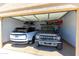 Well-organized garage featuring two parked vehicles, built-in shelving, and ample storage space at 17018 W Saguaro Park Ln, Surprise, AZ 85387