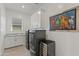 Bright laundry room with modern washer/dryer, stylish cabinets, granite counters, and a charming dog themed art piece at 17018 W Saguaro Park Ln, Surprise, AZ 85387