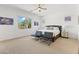 Bright main bedroom with neutral carpet, ceiling fan, and ample natural light from the backyard windows at 17018 W Saguaro Park Ln, Surprise, AZ 85387