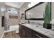 A bathroom featuring a dark vanity with white granite, large mirror, and shower with a tub at 19711 W Colter St, Litchfield Park, AZ 85340