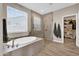 This bright bathroom features a soaking tub and a glass enclosed shower with access to the closet at 19711 W Colter St, Litchfield Park, AZ 85340