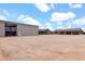 View of the property featuring a spacious gravel area, the home, and a large metal building with equipment at 19711 W Colter St, Litchfield Park, AZ 85340