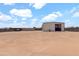 View of the property featuring a spacious gravel area, secure fencing, and a large metal building perfect for storage at 19711 W Colter St, Litchfield Park, AZ 85340