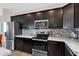 Close-up of the kitchen featuring stainless steel appliances, granite countertops, and dark cabinets at 19711 W Colter St, Litchfield Park, AZ 85340