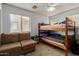 This bedroom has a ceiling fan, window, love seat and a bunk bed at 19719 N Castille Dr, Maricopa, AZ 85138