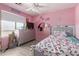 A charming bedroom with pink walls, a ceiling fan and a large window for natural light at 19719 N Castille Dr, Maricopa, AZ 85138