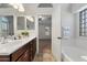 Main bathroom with dual sinks, wood cabinets, a tub, and natural light at 20814 N Dries Rd, Maricopa, AZ 85138