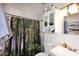 Bathroom with a forest-themed shower curtain, a toilet, a sink, medicine cabinet, and a decorative marble-tiled wall at 2416 W Caribbean Ln # 2, Phoenix, AZ 85023