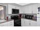 Modern kitchen with white cabinets, sleek black appliances, and stylish gray backsplash at 2416 W Caribbean Ln # 2, Phoenix, AZ 85023