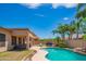 A serene backyard pool with a rock waterfall, lush landscaping, and a comfortable lounge area for relaxation at 26072 N 74Th Ave, Peoria, AZ 85383