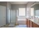 Neutral bathroom featuring double sinks, a relaxing tub, and a separate shower with glass doors, offering practicality at 26072 N 74Th Ave, Peoria, AZ 85383