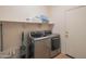 Laundry room with modern washer and dryer, built in shelving, and white door at 26072 N 74Th Ave, Peoria, AZ 85383