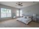 A bright main bedroom with large windows, ceiling fan, carpet flooring, and neutral decor at 26072 N 74Th Ave, Peoria, AZ 85383
