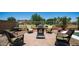 Inviting backyard featuring a brick patio, wrought iron chairs with green cushions, and decorative fire pit at 26135 N Desert Mesa Dr, Surprise, AZ 85387