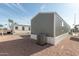 Exterior view of the home's gray siding, white skirting, and central air conditioning unit at 320 E Mckellips Rd # 25, Mesa, AZ 85201