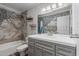 An updated bathroom with stone tile, a gray vanity, and shower-tub combo, offering a modern aesthetic at 428 S Sunnyvale --, Mesa, AZ 85206