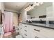 Well-lit bathroom featuring double sinks, modern vanity, and shower with pink curtain at 5354 E Ellis St, Mesa, AZ 85205