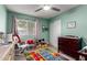 Inviting bedroom with light green walls, window, toys, and a colorful alphabet rug at 5354 E Ellis St, Mesa, AZ 85205