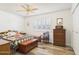 This bedroom features a ceiling fan, a window with plantation shutters, and wood-look floors at 9915 W Mountain View Rd, Sun City, AZ 85351