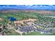Wide aerial view of a golf course community with lush green fairways, a clubhouse, and multiple pools at 119 E Camellia Way, San Tan Valley, AZ 85140