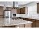 Close-up of a kitchen island with a gas cooktop, granite countertops, and a stainless steel refrigerator at 119 E Camellia Way, San Tan Valley, AZ 85140