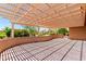 Shaded back patio area featuring a trellis structure with views of landscaped greenery and neighboring homes at 15073 W Piccadilly Rd, Goodyear, AZ 85395