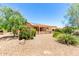 Exterior backyard view showcasing lush desert landscaping, rock features, and a shaded trellis patio at 15073 W Piccadilly Rd, Goodyear, AZ 85395
