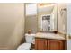 This half bathroom features a granite countertop, wood cabinets, a mirror, and a toilet at 15073 W Piccadilly Rd, Goodyear, AZ 85395