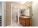 Bathroom showcasing wooden cabinets, granite countertop, double mirrors, and a walk-in closet in the background at 15073 W Piccadilly Rd, Goodyear, AZ 85395