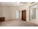 Spacious bedroom featuring neutral walls, carpet floors, a ceiling fan, and access to the bathroom at 15073 W Piccadilly Rd, Goodyear, AZ 85395