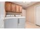 Bright laundry room equipped with white washer and dryer, complemented by dark wood cabinets for storage at 15073 W Piccadilly Rd, Goodyear, AZ 85395