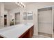 Bathroom featuring double sink vanity, large mirror, wood cabinets, tiled floors and natural light at 1623 E Maplewood Ave, Buckeye, AZ 85326