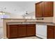This well-lit kitchen offers stainless steel sink, white dishwasher and wooden cabinets, creating an efficient workspace at 1623 E Maplewood Ave, Buckeye, AZ 85326