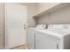 Bright laundry room with washer, dryer, utility shelf, and white door at 1688 W Corriente Dr, San Tan Valley, AZ 85144