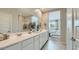 Bright bathroom featuring a double vanity, large mirror, and a glimpse into the bedroom for an open, airy feel at 17387 W Whispering Wind Rd, Surprise, AZ 85387